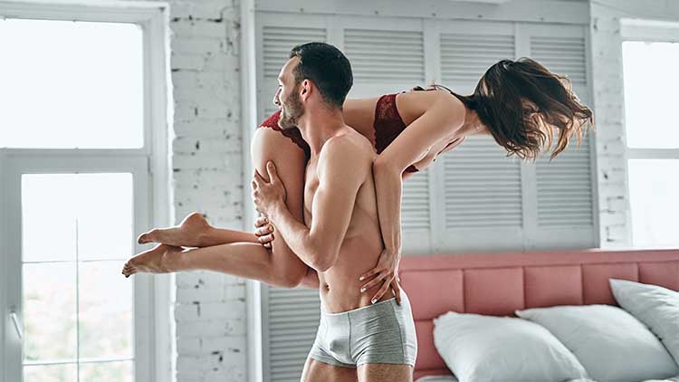 The man carries a happy woman in the bedroom