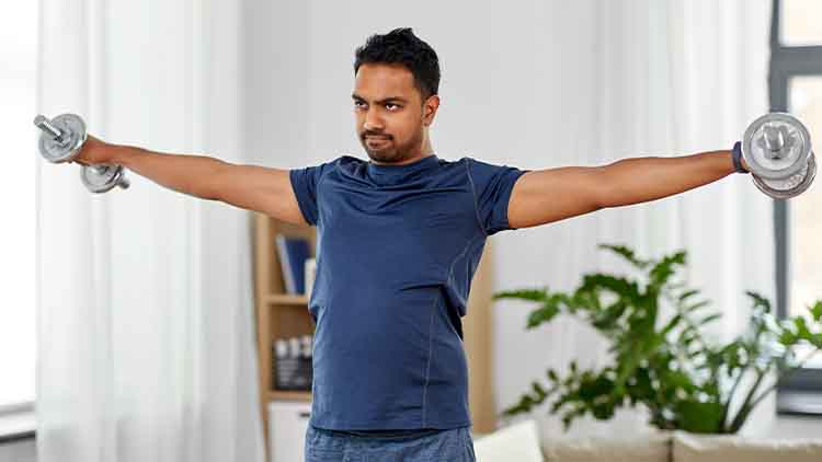indian man exercising with dumbbells at home