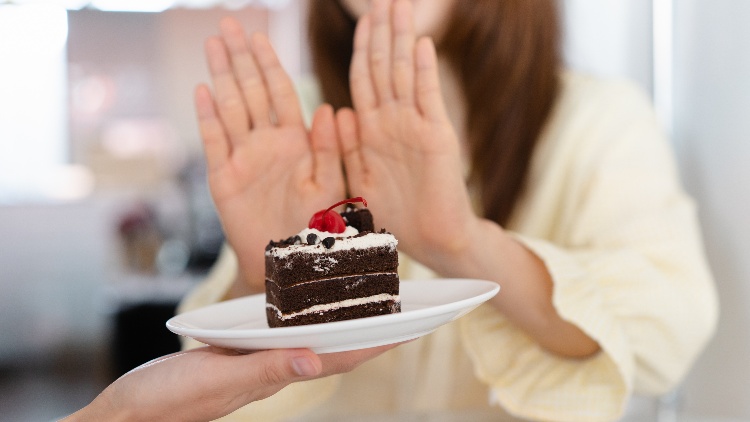 Woman refusing offer of a slice of cake